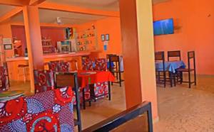 a dining room with orange walls and tables and chairs at Hébergement Centre Culturel Dieufe Dieule in Somone