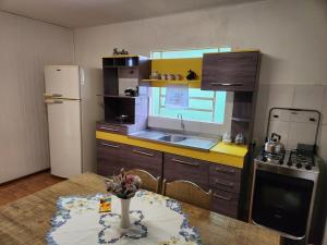 a small kitchen with a table and a refrigerator at Casa Aconchego, espaçosa e bem localizada in Nova Petrópolis