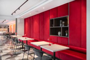 a row of tables in a restaurant with red walls at Tauragė Hotel in Tauragė