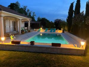 a swimming pool in a backyard at night at Suite dans villa provençale avec parking et piscine in Laneuvelotte