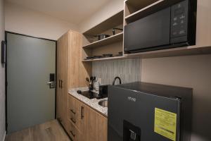 eine kleine Küche mit einem schwarzen Kühlschrank und einer Mikrowelle in der Unterkunft Expo Satélite 2750 Hotel & Suites in Guadalajara