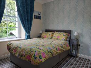 a bedroom with a bed with a colorful comforter and a window at Old School B & B in Llandysul