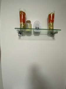 a glass shelf with three jars and a plate at Jmk home in Lexden