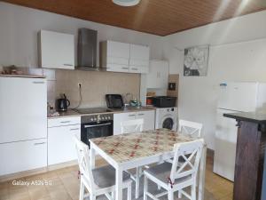 a kitchen with white cabinets and a table and chairs at Rooms Providenca in Gradac