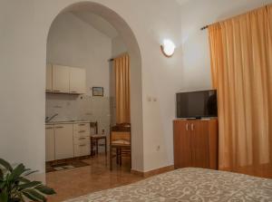a room with a bed and a kitchen with a television at Huter Apartments in Herceg-Novi