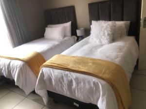 two beds in a room with white sheets and pillows at Cass Villa 25 Kimberley in Kimberley