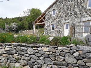 a stone wall in front of a stone house at Maison de village gîte de "La Roche" in Saint-Julien-Chapteuil