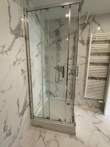 a glass shower in a bathroom with white marble at Studio Côte Bleue in Boulogne-sur-Mer