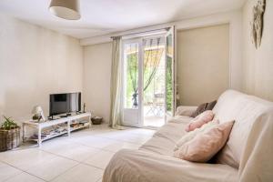 Una sala de estar con un sofá y un televisor. en La Villa Jasmin, en Montauroux