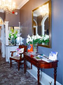 a table with a mirror and a vase of flowers at East Walls Hotel in Chichester