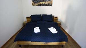 ein Schlafzimmer mit einem Bett mit blauer Decke und weißen Schuhen in der Unterkunft Kokavská izba - Apartmány in Kokava na Rimavica