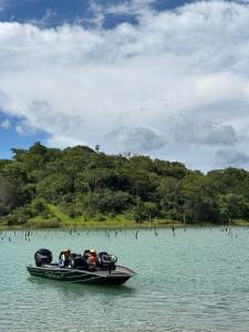 Ein Boot mit zwei Leuten im Wasser. in der Unterkunft Rancho do Guila Pesca & Diversão Corumbá 3 in Abadiânia