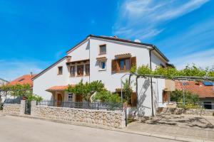 a white house with a stone wall at Apartments Anci in Mali Lošinj