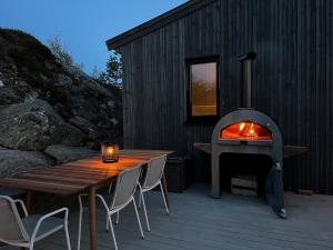 a wood fired pizza oven sitting next to a wooden table and aburning at Great cottage with unique views and high standard in Tørhogg