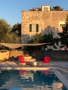 a pool with two chairs and a hammock and a house at Casettina Matilda in Ostuni