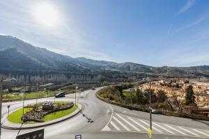 an empty road in a city with mountains in the background at Apartamentos Sendero del Veleta in Cenes de la Vega
