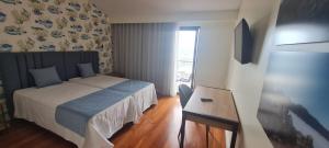 a bedroom with a bed and a desk and a television at Casa Linda Baía in Porto da Cruz