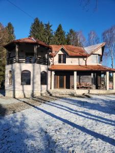 una casa vieja en la nieve con árboles en el fondo en Cabana Dealul Negru, en Dealu Negru