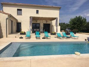 a swimming pool with blue chairs and a house at Maison avec vue et sa piscine chauffée privative in Bessas