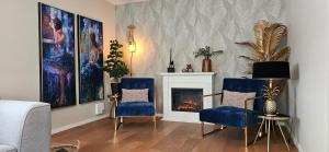 a living room with two blue chairs and a fireplace at Cottage Heuvelland in Hulsberg