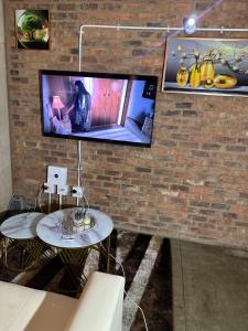 a tv hanging on a brick wall with two tables at The Hills by maboneng in Johannesburg +9 photos