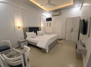 a white bedroom with a bed and a television at JD Heritage Inn in Bareilly