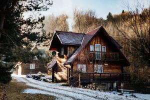 a log cabin in the winter with snow on the ground at Domki u Serowarki z Jacuzzi w cenie in Polańczyk