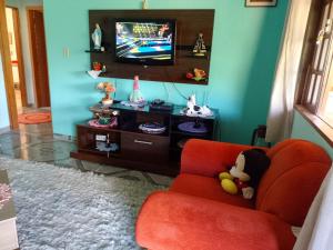 un soggiorno con sedia rossa e TV di Casa de Campo - Vista Exuberante São Bento do Sapucaí a São Bento do Sapucaí