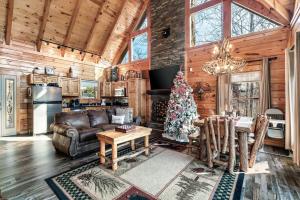 a living room with a christmas tree in a log cabin at 8 Beds, Hot Tub, Fireplaces, Pool Tbl Arcade VIEWS! in Sevierville