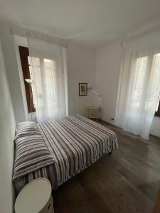 a bedroom with a bed with a striped comforter and two windows at Testaccio Stay - your home in the heart of Rome in Rome