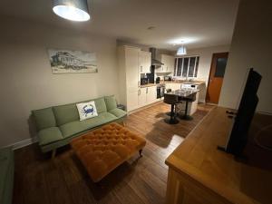 a living room with a green couch and a stool at Pebble Cottage in Golspie