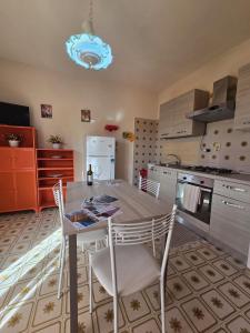 een keuken met een tafel, stoelen en een koelkast bij Regina Elena Apartment in Marzamemi