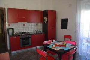 a kitchen with red cabinets and a table with red chairs at casa vacanze ilcieloprivato in Calasetta