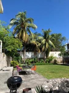 einen Grill mit Stühlen, einem Tisch und Palmen in der Unterkunft CoCo Cozy Apartment Centric and Private in Cozumel + 17 Fotos