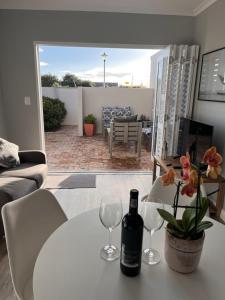 een witte tafel met twee glazen en een fles wijn bij Cozy Cottage in Kaapstad
