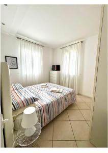 1 dormitorio con 1 cama con colcha a rayas en Appartamento Sul Mare, en Riccione 4 fotos más