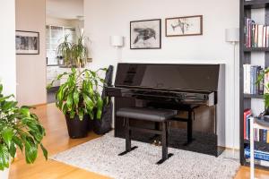 a black piano in a living room with plants at Private room with views to the mountains in Reykjavík