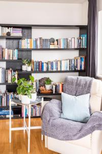 a living room with a chair and a book shelf with books at Private room with views to the mountains in Reykjavík