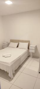 a white bedroom with a bed and two night stands at Casa aconchegante in Guanamby