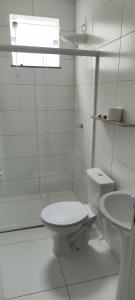 a white bathroom with a toilet and a sink at Casa aconchegante in Guanamby +8 photos