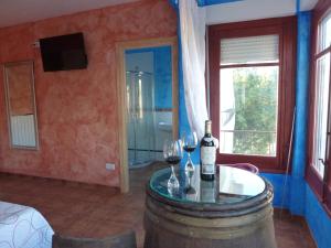 a room with a barrel and two glasses of wine at Hostal A La Sombra Del Laurel in Navarrete