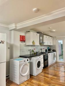 ColindaleにあるComfy Double Room in Colindale With Shared Bathroomのキッチン(白いキャビネット、洗濯機、乾燥機付)