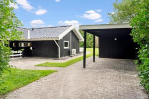a black house with a garage and a brick driveway at Summer House Close To Nature And Beach in Dronningmølle