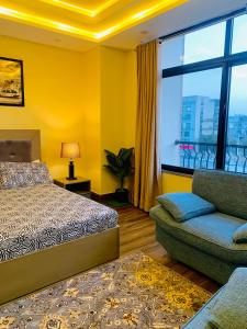 a bedroom with a bed and a couch and a window at Azure Atrium Abode one bedroom family apartment in Rawalpindi