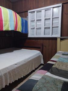 two beds in a room with a window at Casa na praia do sonho in Palhoça