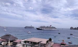 卡波圣卢卡斯Medano Beach suites的两艘游轮在水中与建筑物