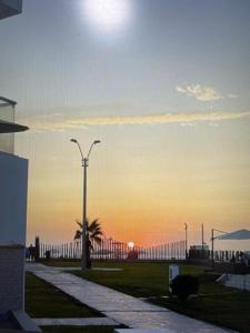 a street light with a palm tree and the sunset at Hermosa casa de playa Asia in Lima +2 photos