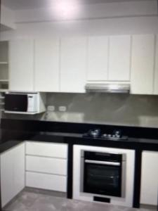 a kitchen with white cabinets and a stove top oven at Hermosa casa de playa Asia in Lima