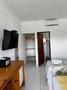 a room with a bed and a tv on the wall at Suítes Cantinho do Ze em Milagres in São Miguel dos Milagres