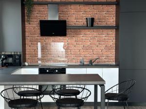 a table with chairs and a television on a brick wall at KOA - Moon Penthouse in Braşov